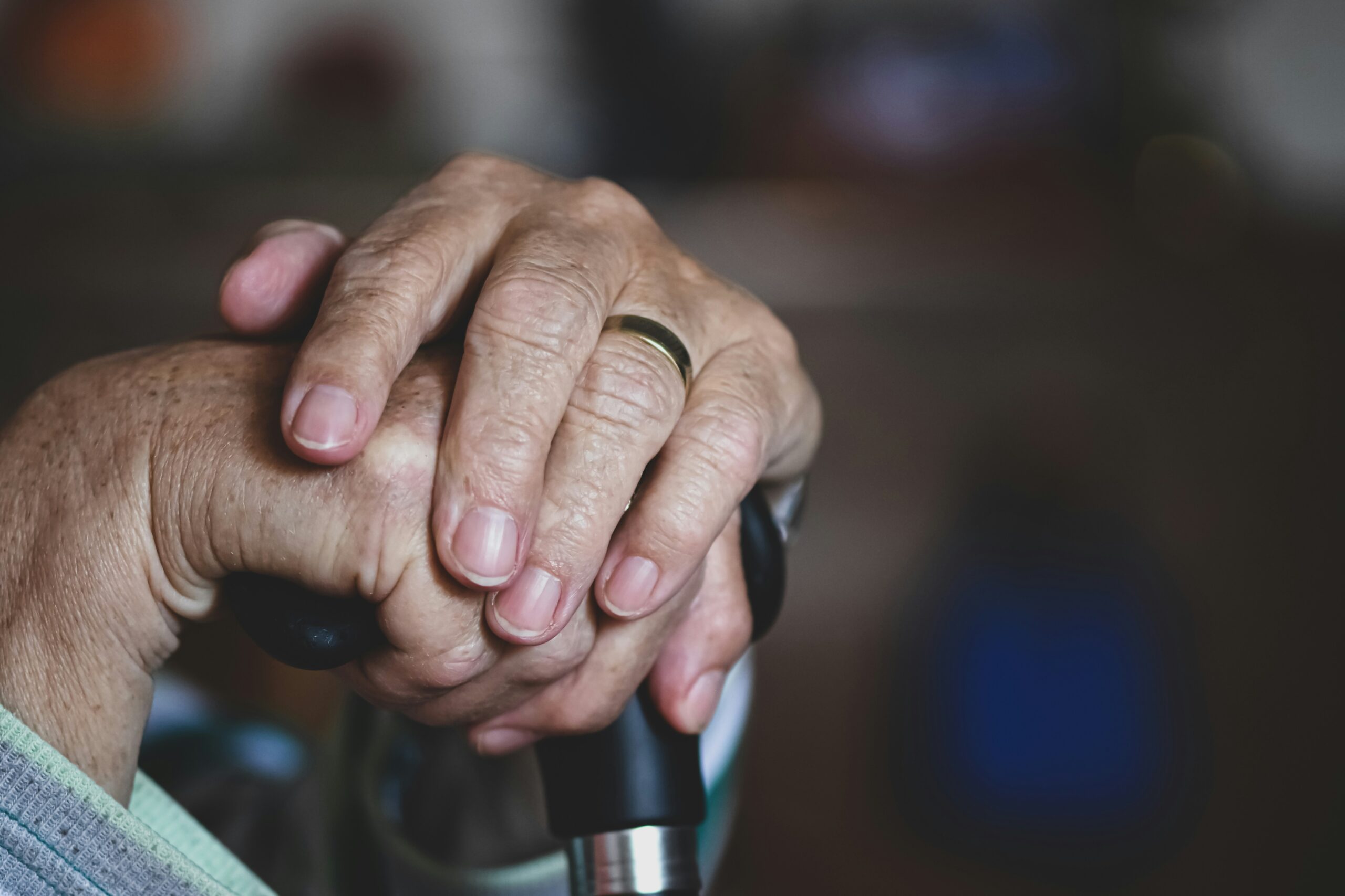 Gros plan sur les mains d'une personne âgée reposant sur une canne, une bague en or brillant à un doigt. L'image évoque l'âge, le soutien et la contemplation, reflétant les moments où l'aide ménagère du CESU peut apporter confort et indépendance.