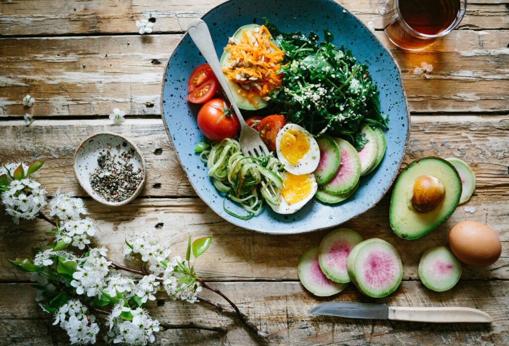 Un saladier coloré avec des légumes verts, du quinoa et des légumes repose sur une table en bois rustique - parfait pour un déjeuner nourrissant avant que votre aide ménagère CESU n'arrive pour vous aider à organiser votre maison et à la rendre accueillante.