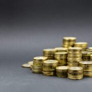 Des piles de pièces d'or, disposées en pyramide sur une surface plane et grise, illustrent la richesse ou l'épargne - ce qui souligne l'importance de connaître le coût réel aide à domicile après aides pour planifier les dépenses futures et gérer les ressources de manière efficace.