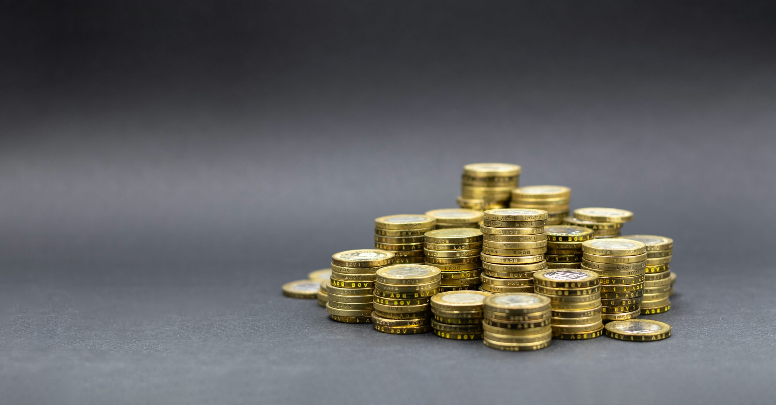 Des piles de pièces d'or, disposées en pyramide sur une surface plane et grise, illustrent la richesse ou l'épargne - ce qui souligne l'importance de connaître le coût réel aide à domicile après aides pour planifier les dépenses futures et gérer les ressources de manière efficace.
