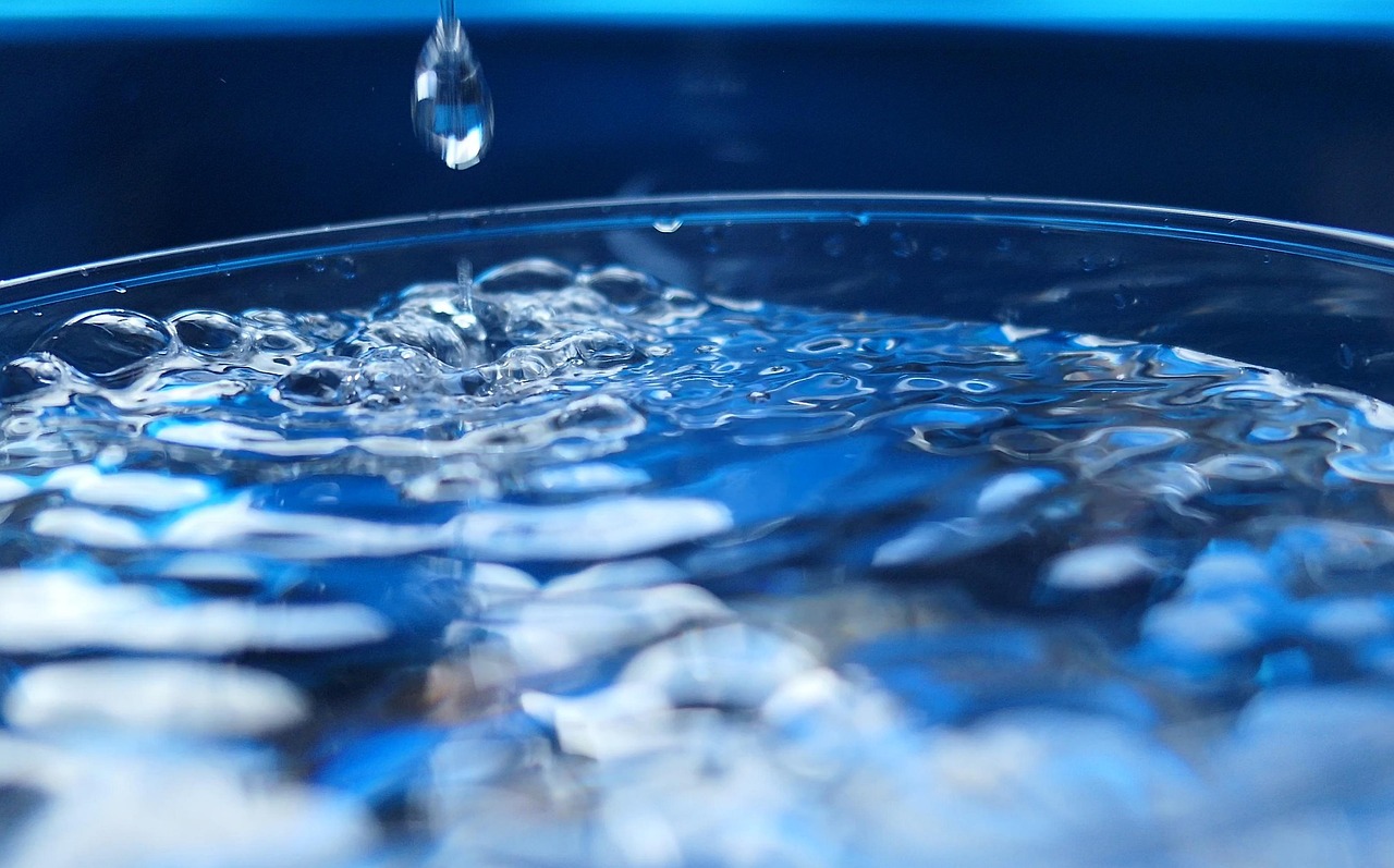 Une simple goutte d'eau tombe dans un verre, créant des ondulations et des bulles : une image rafraîchissante qui illustre les bienfaits pour la santé d'arrêter de fumer après 60 ans.