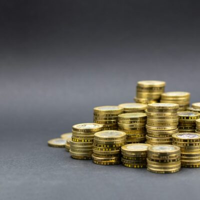 Des piles de pièces d'or, disposées en pyramide sur une surface plane et grise, illustrent la richesse ou l'épargne - ce qui souligne l'importance de connaître le coût réel aide à domicile après aides pour planifier les dépenses futures et gérer les ressources de manière efficace.
