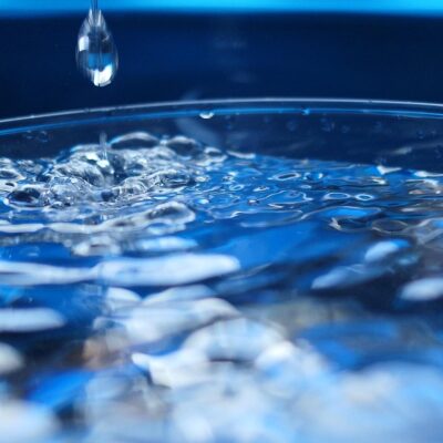 Une simple goutte d'eau tombe dans un verre, créant des ondulations et des bulles : une image rafraîchissante qui illustre les bienfaits pour la santé d'arrêter de fumer après 60 ans.