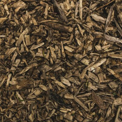 Vue rapprochée d'un tas de copeaux de bois bruns et de paillis, idéal pour l'entretien du jardin ou l'utilisation par une aide ménagère du CESU, montrant des morceaux de bois rugueux et déchiquetés de différentes formes et tailles.