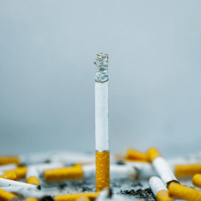 Une seule cigarette à l'extrémité brûlée est entourée de plusieurs cigarettes brisées et éparpillées sur un fond clair, rappelant le processus minutieux nécessaire pour nettoyer un Thermomix après une utilisation intensive.